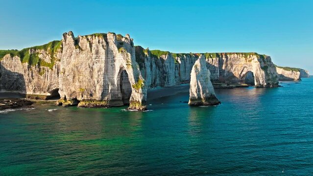 Aerial view of Towering white cliff featuring natural arch by the sea in France. Scenic view of Falaise d'Aval in Etretat, France. Rock formation by the water edge, scenic point tourist attraction.