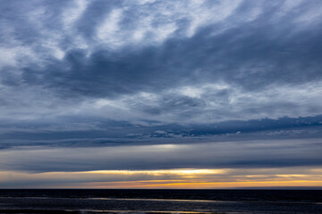 Dark rain clouds over sea horizon at sunset