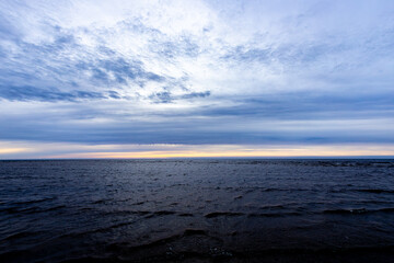 Dark rain clouds over sea horizon at sunset