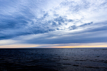 Dark rain clouds over sea horizon at sunset
