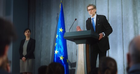 Female representative of media asks question to European politician performing at press conference. Confident EU consul makes an announcement, delivers campaign speech, gives interview. Election day. - obrazy, fototapety, plakaty