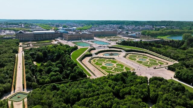 Aerial view of Immense French palace with gilded apartments, chandeliered Hall of Mirrors and fountain show. Fortress castle, Palace of Versailles drone aerial view with landscaped gardens in France.