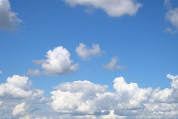 Naklejka na ściany i meble An endless blue sky with white clouds floating over the horizon. Panoramic view of the cloudy sky. Cumulus white clouds. Cloudy weather.