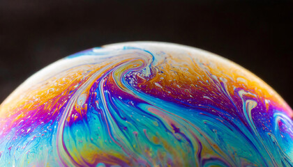 A close up view of Vibrant soap bubble displaying a spectrum of iridescent colors on a similar hued surface.