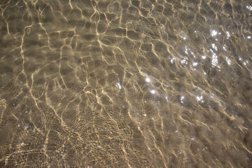It is transparent with sparkles of the sun and a sandy bottom.