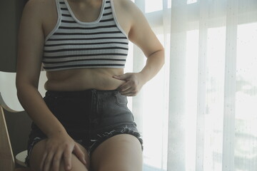 Women body fat belly. Obese woman hand holding excessive belly fat. diet lifestyle concept to reduce belly and shape up healthy stomach muscle. - obrazy, fototapety, plakaty