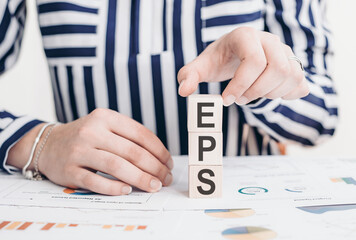 A woman holding a block with the word EPS on it, representing Earnings Per Share, a financial...