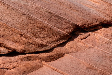Layers of reddish sandstone with a sloping layer sequence and a rough surface. Close-up of rocks...