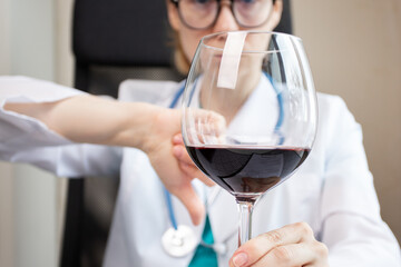 doctor refuses alcohol, shows thumbs down to glass of wine, no alcoholic drinks, boozing refusal, health care - obrazy, fototapety, plakaty