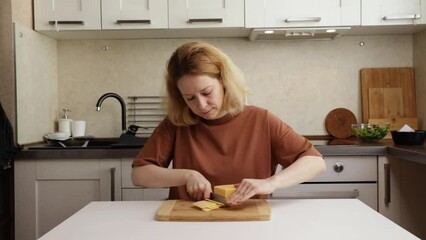 Woman cooking at home, cutting dairy product for lunchtime meal in the kitchen.