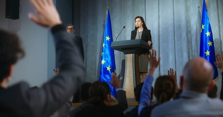 Female politician comes to tribune, delivers campaign speech, answers journalists questions, gives interview to media. Representative of the European Union performs at press conference. Elections day. - obrazy, fototapety, plakaty