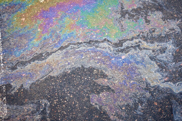 Marble spills on water from gasoline and oil stains. Abstract background from spilled motor oil, gas or gasoline on the asphalt.