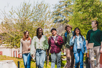A diverse group of university students enjoy a sunny day on campus - friends walking and laughing...