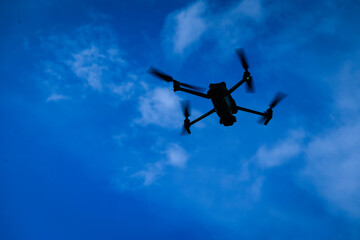 Drone flying overhead in cloudy blue sky, High quality photo
