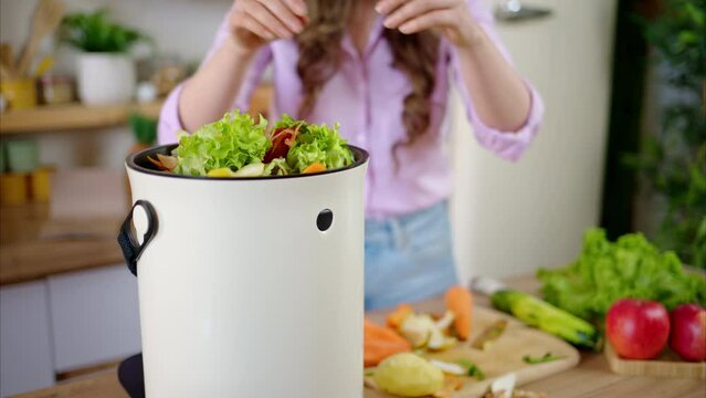 Woman recycling organic waste by composting vegetables peels in the Bokashi in the kitchen