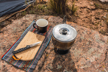 set of camping utensils pots knife knife cup and chopping board placed on the vegetation in the...