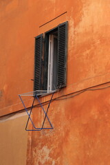 Orange Building Facade with Open Window and Drying Rack in Rome, Italy