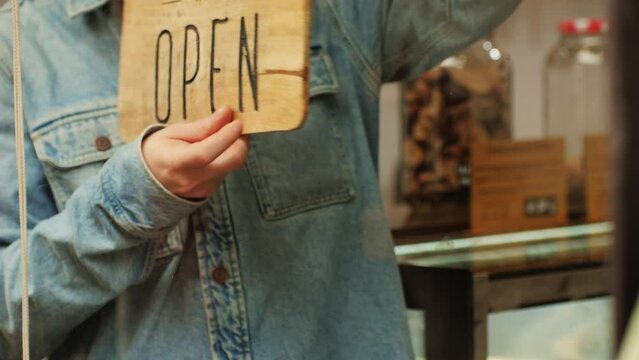 Young man worker flipping sign closed to open close-up. Turn sign to open at the beginning of day. Worker opening cafe, restaurant or shop. Small business development concept.