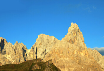 mountain in the Italian Dolomites called Cimon della Pala glows with warm orange hues at sunset ...