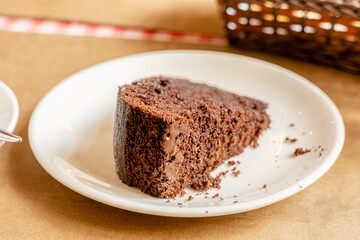 Fototapeta na wymiar Piece of fresh homemade chocolate sponge cake on white plate on the table