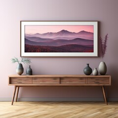 The setting sun casts a pink hue on the mountain landscape framed on the wall above a mid-century modern credenza