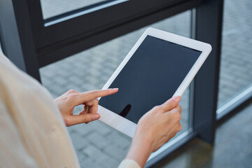 A businesswoman in a modern office confidently holds and interacts with a tablet, embodying the franchise concept.