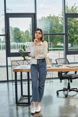 A modern businesswoman stands confidently in front of a sleek table in a contemporary office...