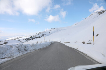 slippery mountain road with snow on the sides and posts to mark the limit of the roadway - obrazy, fototapety, plakaty