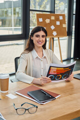 A businesswoman in a modern office, sitting at a table, immersed in reading charts near her...