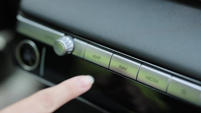 Close-up view of car interior. View of car map navigation button. Driver pressing map button of electric car. GPS Navigation map system screen in the car for travel