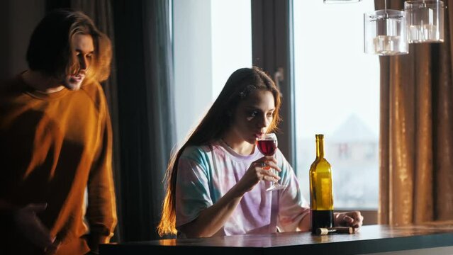A man yells at and argues with his girlfriend because of her drinking problem. Despite this, she continues to drink wine and does not seem to care. Mid shot. 4k