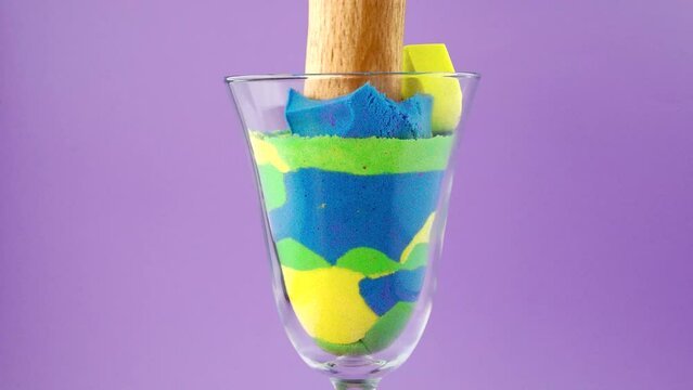 Crush of kinetic sand in a glass on a white background. Very Satisfying and Relaxing Kinetic Sand ASMR video. Cutting anti stress macro close up colorful Kinetic Sand with a Knife. ASMR sounds.