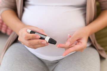 Obraz na płótnie Canvas Pregnant woman checking blood sugar level by using Digital Glucose meter, health care, medicine, diabetes, glycemia concept