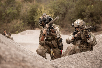 Soldiers in camouflage uniforms aiming with their rifles.ready to fire during military operation in...