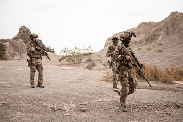 Naklejka premium Soldiers in camouflage uniforms aiming with their rifles.ready to fire during military operation in the desert , soldiers training in a military operation