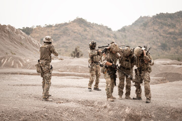 Soldiers in camouflage uniforms aiming with their rifles.ready to fire during military operation in...