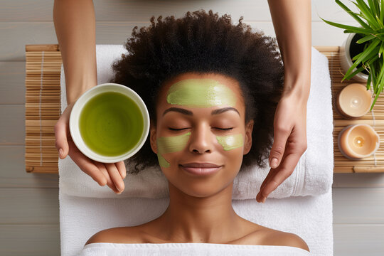 An ethnic African woman lying in a beauty salon receiving a natural herbal facial treatment. Beauty, natural and personal care treatment.