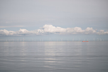 Heavy Rainy Clouds Over Calm Sea With Wind Generators In The Background