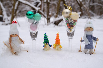 Two glasses with Christmas balls and Christmas angels with gnomes. New Year decorations.
