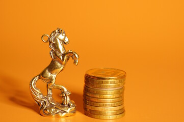 A statuette of a metal horse with coins on the table. Finance and economics.