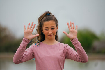 Portrait of a girl showing hands outdoors.