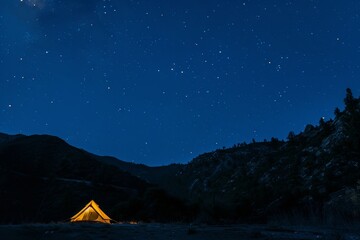 Tent glowing under mountain stars