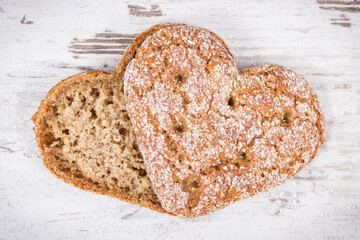 Fresh wholegrain bread in shape of heart for breakfast. Old rustic background