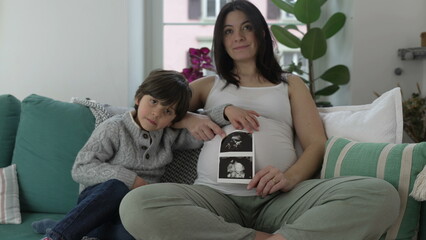 Happy Mother and Child Posing with Ultrasound Picture - Smiling at Camera with Unborn Baby...