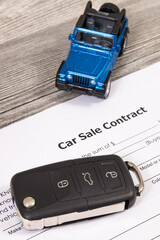 Form of car sale agreement, blue toy car and key. Sales, purchases new or used vehicle