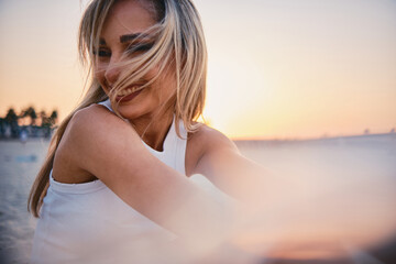 The image captures the contemplative silhouette of a woman in white facing a beautiful sunset,...