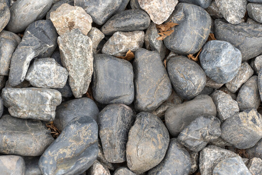Heap grey stone for design in park and garden. Geometric pebbles close-up. Texture gravel and nature stone background. Roundish mineral.