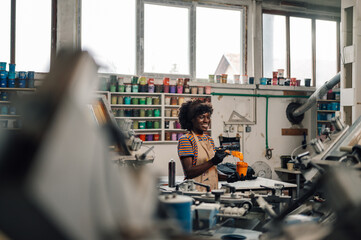 Interracial worker working with paint at silkscreen printing workshop.