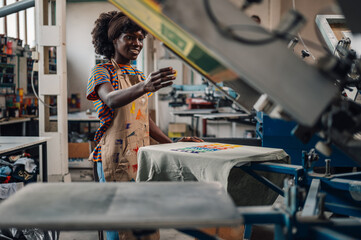 Smiling interracial print shop worker finishing serigraphy on textile.