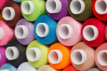multi-colored spools of sewing thread on a white background